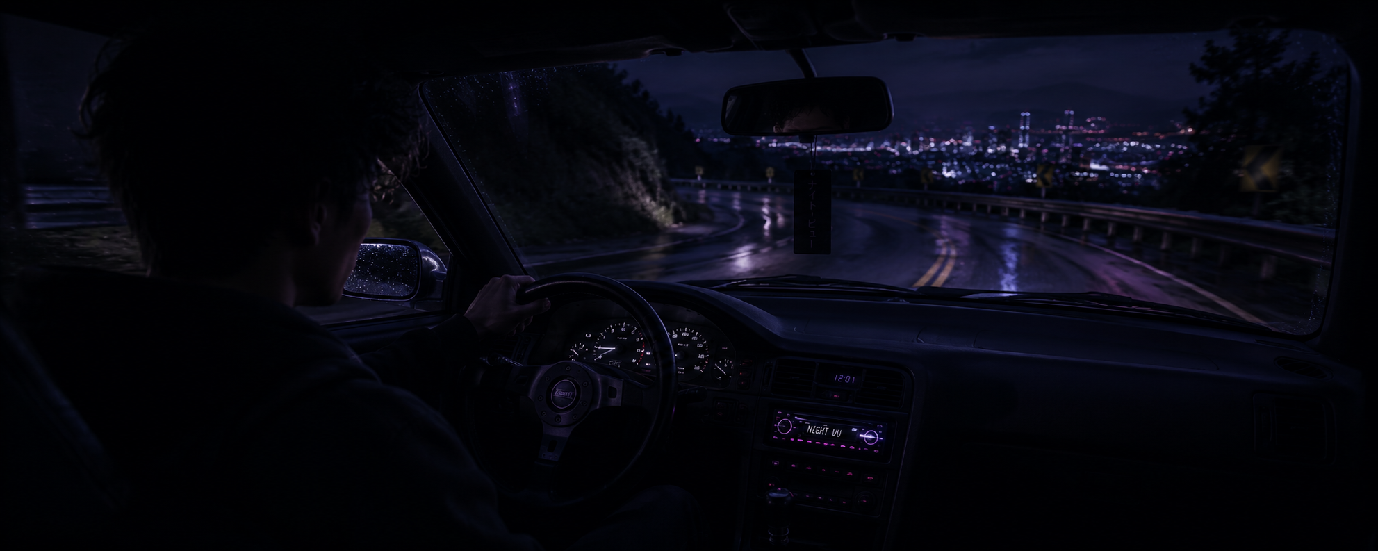 Driver wearing Night VU glasses while driving at night on a wet, winding road with soft purple dashboard light and distant city lights ahead.